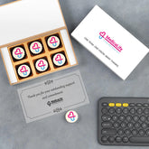 Open wooden box with six logo chocolates—elegant corporate gift for distributors.