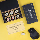 Open black MDF box with six logo chocolates and thank‑you butter paper for top performer.