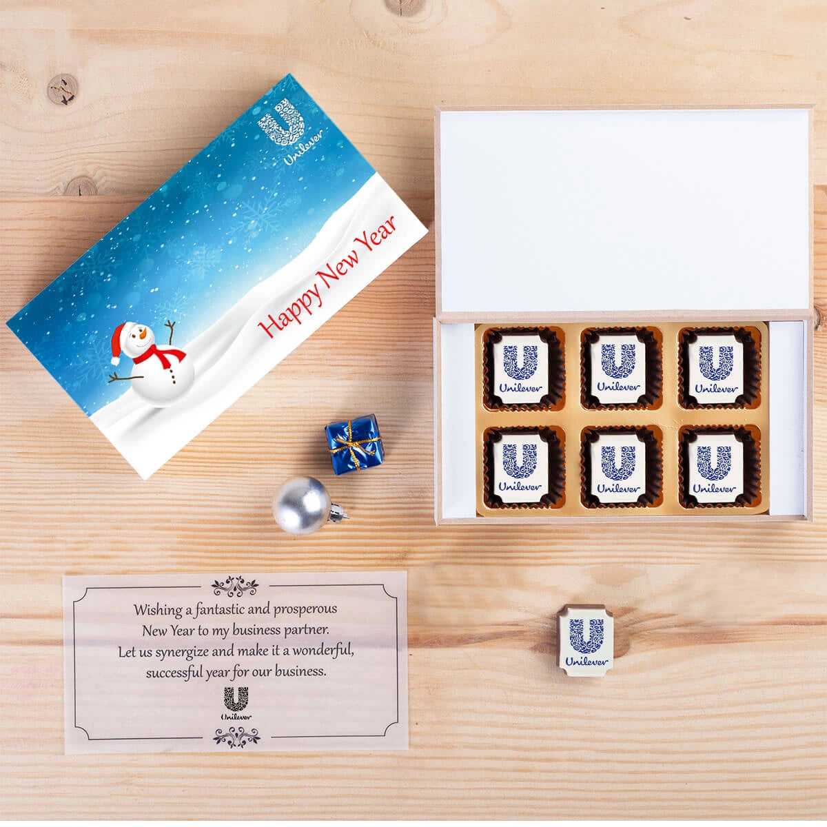 Open wooden gift box with custom‑printed logo chocolates and personalized greeting inside lid.