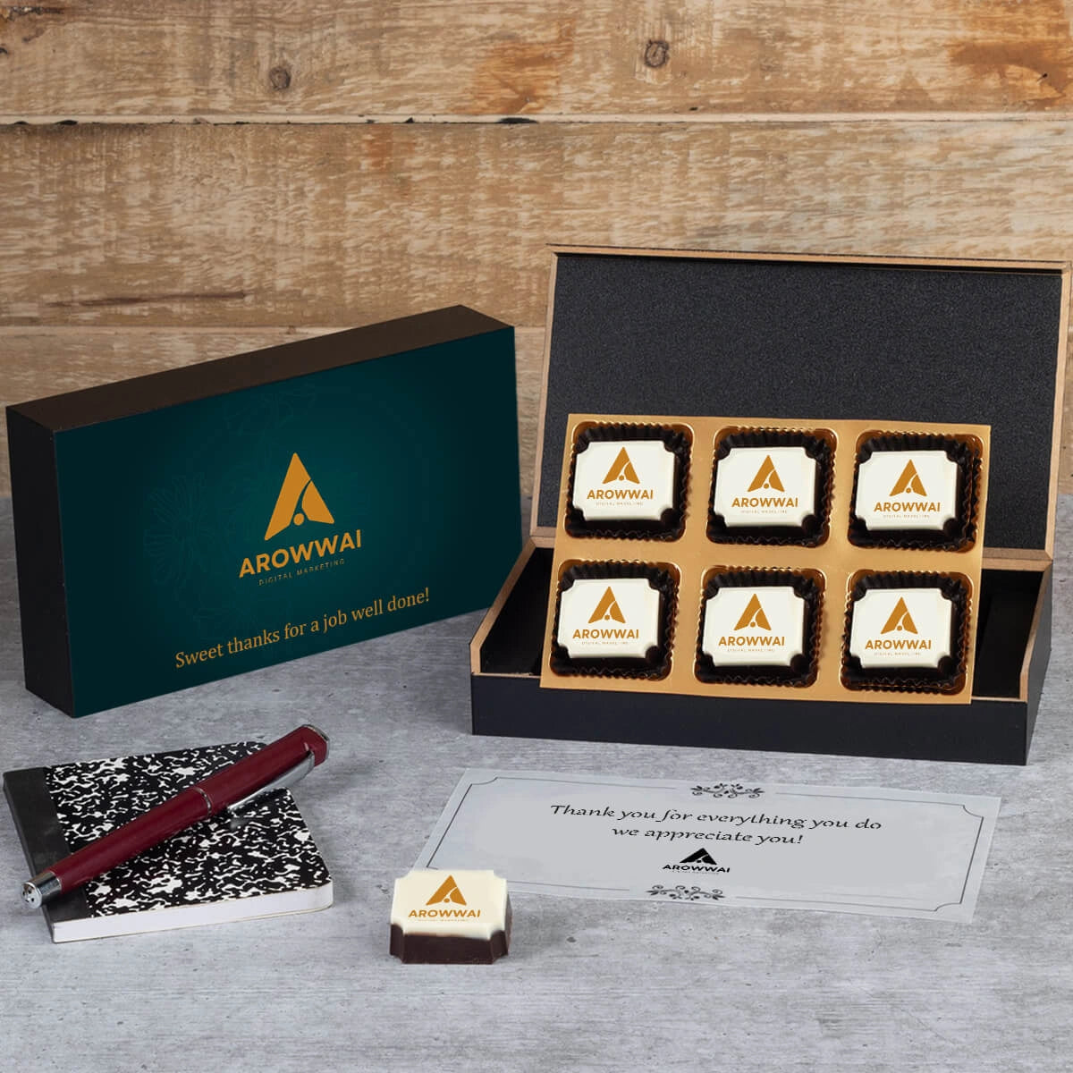 Open MDF box revealing six logo chocolates and thank‑you note for employees.