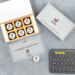 Six‑piece edible‑logo chocolate box celebrating staff promotion achievements